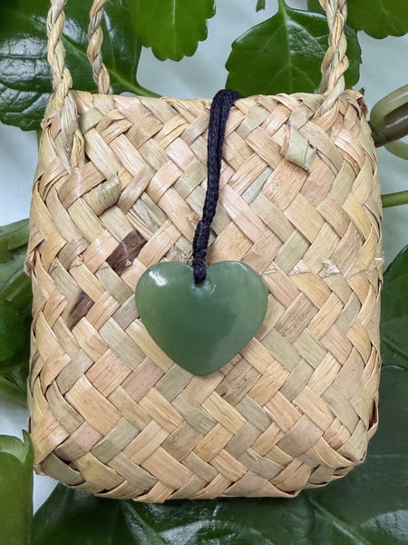 Heart-shaped greenstone pendant on a woven flax bag