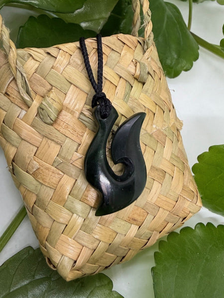 Greenstone fish hook pendant on a woven flax bag