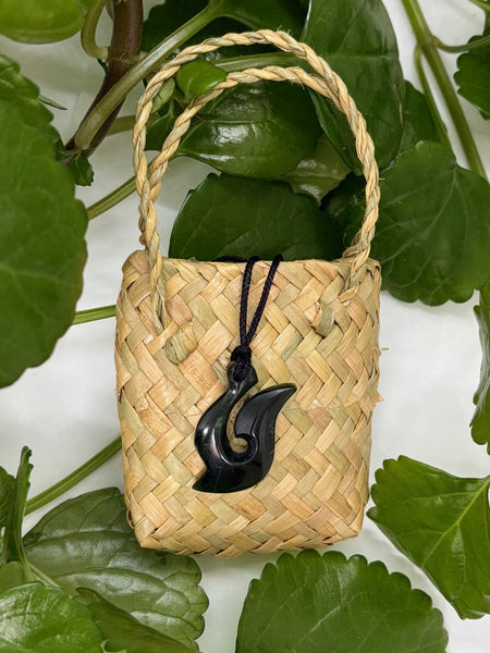 Greenstone fish hook pendant on a woven flax bag