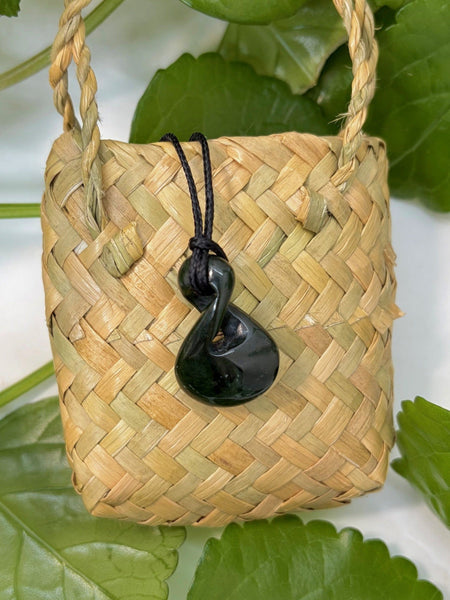 Greenstone pendant with a black cord on a woven flax bag
