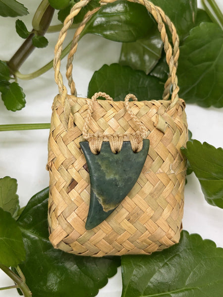 Greenstone tooth Pendant with bound cord on a woven flax bag.